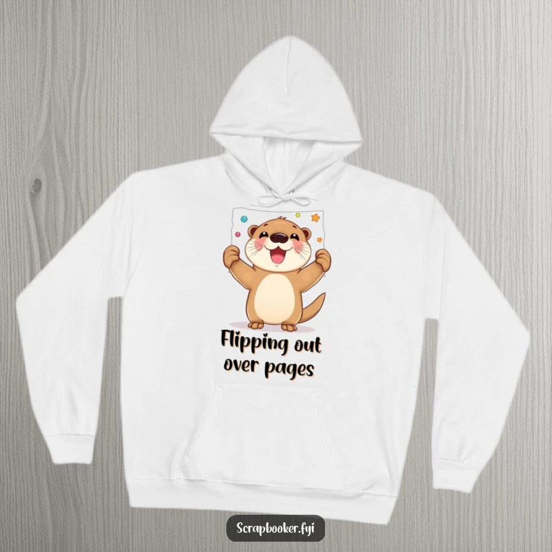 Funny hoodie featuring a joyful otter proudly holding up a decorated page, symbolizing artistic achievement and happiness.