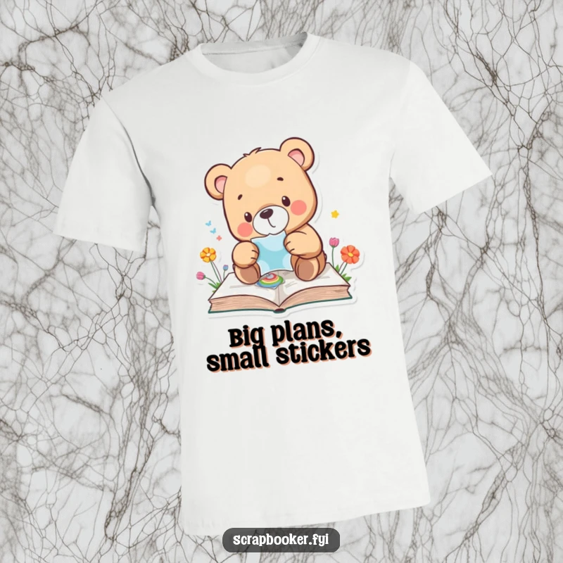 Funny bear t-shirt with a bear carefully applying a sticker to a colourful page, showing focus and creativity. Perfect gift.