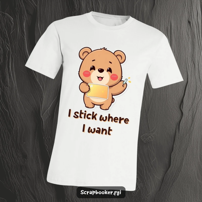 Funny T-shirt featuring a cheerful bear carefully gluing a shiny sticker into place, celebrating creativity and meticulous artistry.